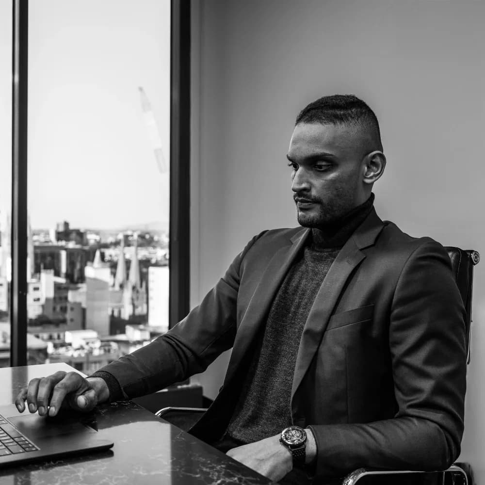 Tav Palapathwala at his desk beside a window overlooking Melbourne.